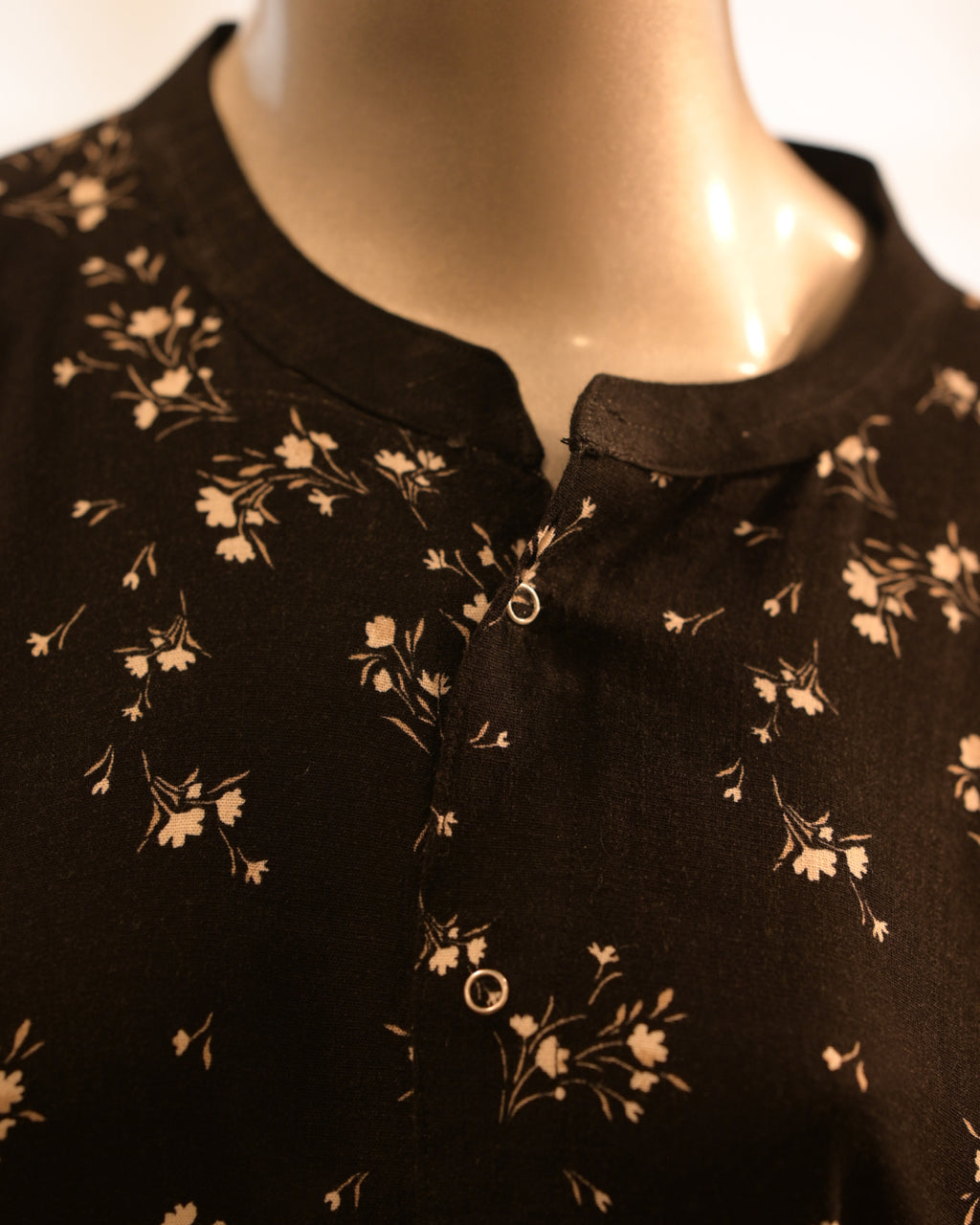 Black floral-patterned dress on a mannequin with a white background